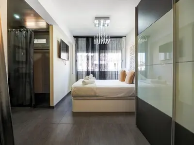 a bedroom with a bed and a bathroom with a window at Atalaya Apartment by Hello Homes Sitges in Sitges