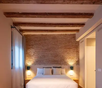 a bedroom with a white bed and a brick wall at Casa Badajoz in Barcelona