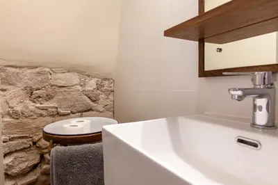 a bathroom with a sink and a stone wall at Cal Simon- Casa a Montserrat in Collbató