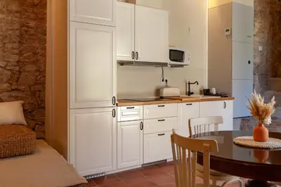 a kitchen with white cabinets and a dining table at Cal Simon- Casa a Montserrat in Collbató