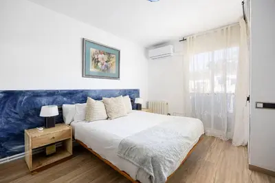 a bedroom with a large bed with a blue headboard at House 5 Mins From Montgat Beach in Montgat