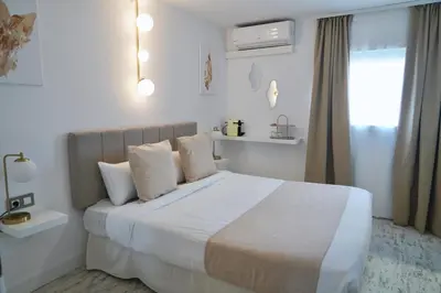 a white bedroom with a bed with white sheets and pillows at Aldara Sitges in Sitges