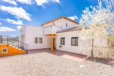 a bedroom with a large bed and a blue chair at Villa Serranita - Stylish Holiday Home with Views and Air Conditioning 15 mins to Sitges in Olivella