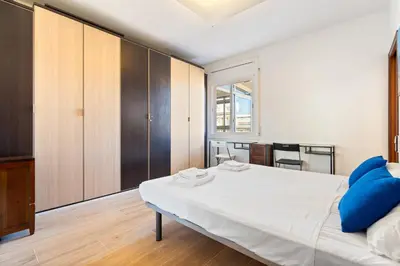 a bedroom with a white bed and wooden cabinets at Sunny 3BR2BA w Private Terrace AC in Barcelona