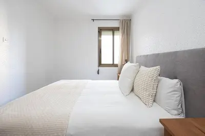 a bedroom with a bed with white sheets and a window at Cozy Apt In Cornella 2 Mins From The Metro in La Gabarra