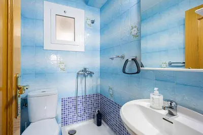 a blue tiled bathroom with a toilet and a sink at Cozy Apt In Cornella 2 Mins From The Metro in La Gabarra