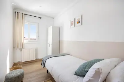a white bedroom with two beds and a window at Amazing 3bdr Apt In Cornella 1 Mins From Metro in Cornellà de Llobregat