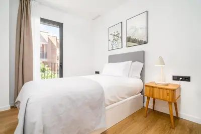 a white bedroom with a bed and a window at Limehome Barcelona Plaça Pirineus in Hospitalet de Llobregat