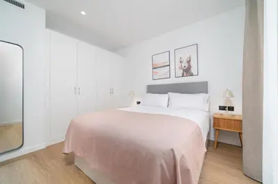 a white bedroom with a large bed and a table at Limehome Barcelona Plaça Pirineus in Hospitalet de Llobregat