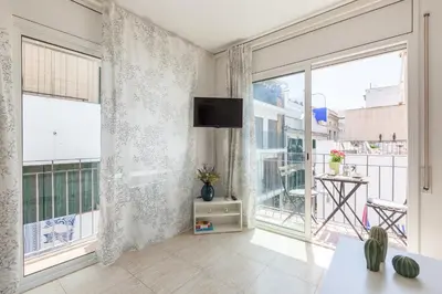 a living room with large windows and a flat screen tv at Nova Apartment by Hello Homes Sitges in Sitges