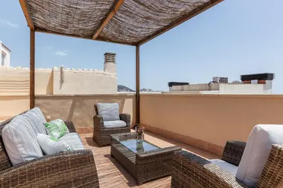 a patio with wicker chairs and a table on a roof at SOUL by Hello Homes Sitges in Sitges