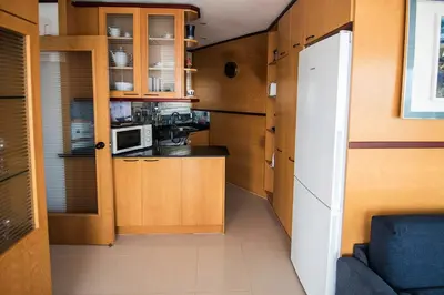 a small kitchen with wooden cabinets and a microwave at Sitges Views in Sitges