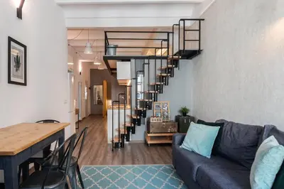 a living room with a couch and a spiral staircase at Beautiful renovated Loft minutes from the beach in Barcelona