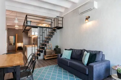 a living room with a couch and a spiral staircase at Beautiful renovated Loft minutes from the beach in Barcelona