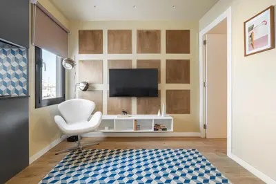 a living room with a white chair and a television at Sagrada Familia Apartment by Olala Homes in Barcelona