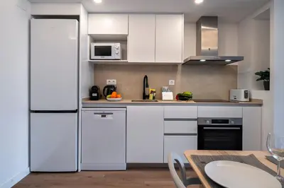 a white kitchen with white cabinets and a table at Habitat Apartments Teatre in Hospitalet de Llobregat