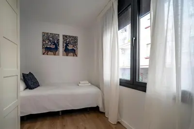 a white room with a bed and a window at Habitat Apartments Teatre in Hospitalet de Llobregat