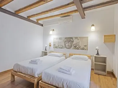 two beds in a room with white walls and wooden floors at Las Ramblas, comfort in BCN for 8 persons in Barcelona
