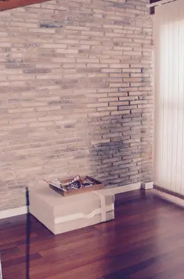 a room with a brick wall and a white bench at CasaOller in Manresa