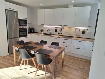 a kitchen with white cabinets and a wooden table and chairs at Casa Natura Montseny in El Brull