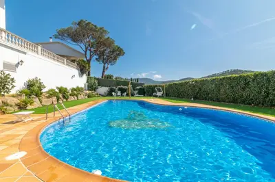 a large pool with blue water in a yard at Large 5-Bed Villa, mountain and beach, at 30' from Barcelona & 10' from F1 Circuit in Vallromanas
