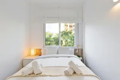 a white bedroom with a bed with towels on it at Suites Barcelona Park Güell in Barcelona