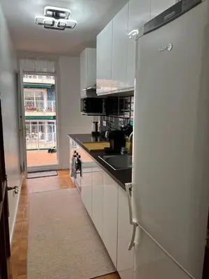 a kitchen with white cabinets and a refrigerator at Logement avec vue latérale mer in Pineda de Mar
