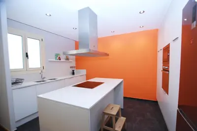 a kitchen with a white counter and an orange wall at Sant Guillem in Vilassar de Mar