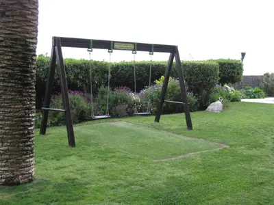 a swing set in a garden with flowers at Apartment La Rosa (Blaumar) in Sant Andreu de Llavaneres