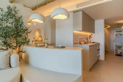 a kitchen with two pendant lights and a living room at Apartamentos Azul in Castelldefels