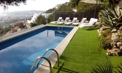 a swimming pool with chairs and a lawn at The Villa Sunlight in Sitges