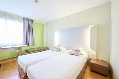 a hotel room with two beds and a window at Travelodge BCN Cornella Fira in Cornellà de Llobregat