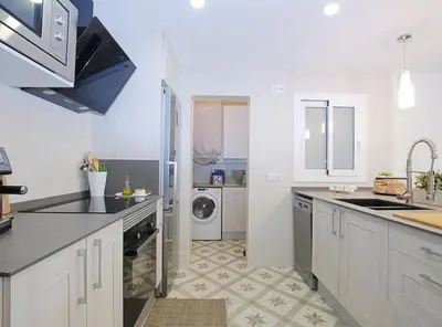 a white kitchen with a sink and a dishwasher at Cel i Mar Canet in Canet de Mar