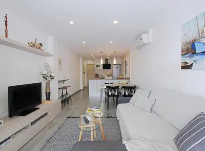 a living room with a white couch and a kitchen at Cel i Mar Canet in Canet de Mar