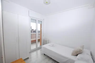 a white bedroom with a bed and a window at Narciso views in Vilassar de Mar