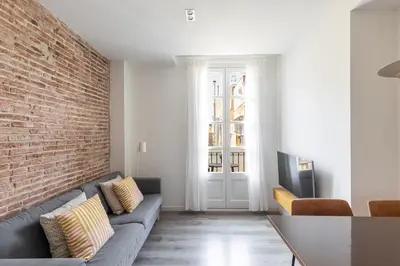 a living room with a couch and a brick wall at Decô Apartments Barcelona-Sants in Barcelona