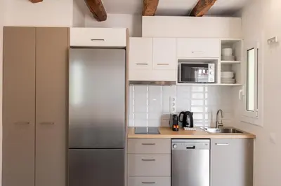 a kitchen with white cabinets and a stainless steel refrigerator at Decô Apartments Barcelona-Sants in Barcelona