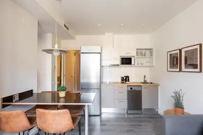 a kitchen with white cabinets and a table and chairs at Decô Apartments Barcelona-Sants in Barcelona