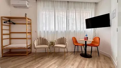 a living room with a table and chairs and a television at Crysoyle Apartment II Barcelona Next to Camp Nou in Hospitalet de Llobregat
