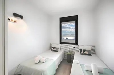 a white room with two beds and a window at Seaside Badalona Apartment in Badalona