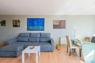 a living room with a blue couch and a table at Casa Mar Blava con piscina comunitaria junto Barcelona Centro in Alella