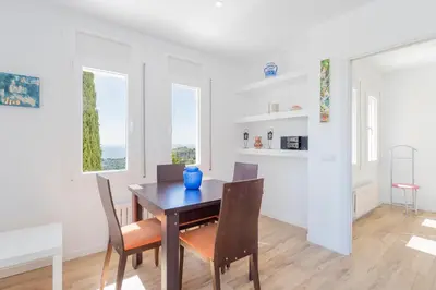 a dining room with a table and chairs and windows at Casa Mediterrani & piscina comunitaria junto Barcelona in Alella