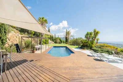 a swimming pool on a wooden deck with a table and chairs at Casa Mediterrani & piscina comunitaria junto Barcelona in Alella