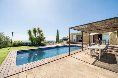a swimming pool with a table and a house at Casa Mediterrani & piscina comunitaria junto Barcelona in Alella