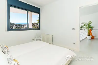 a bedroom with a white bed with colorful pillows at Super Villa Oasis Fab Sea and Sitges View with Private Pool and Air Conditioning in Sitges