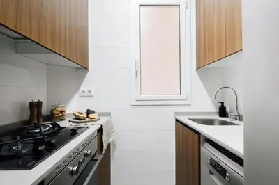 a kitchen with white walls and wooden cabinets at Bari - 2 bedroom and office in Sant Antoni in Barcelona
