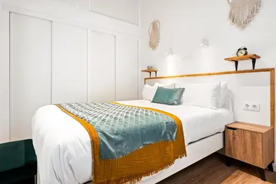 a bedroom with a white bed with a wooden headboard at Lodging Apartments Almirall Beach 11 in Barcelona