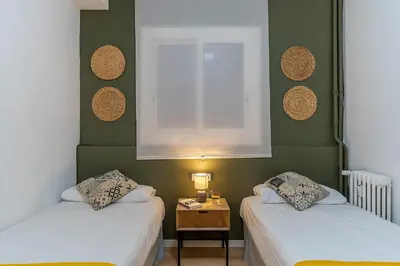 a room with two beds and a table with a window at 1774 - AB Saint Joseph Apartment in Barcelona