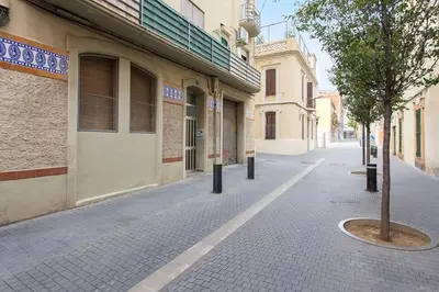 an empty street with a tree on the side of a building at Cozy And Quiet In Trendy Sants in Barcelona