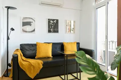 a living room with a black couch and yellow pillows at Relax In A Chic Apartment In Sants in Barcelona